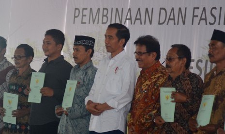 Presiden Joko Widodo (tengah) didampingi Menteri Agraria dan Tata Ruang/Kepala BPN Sofyan Djalil (ketiga kanan) berfoto bersama warga seusai penyerahan secara simbolis sertifikat hak atas lahan tanah di lapangan Pemerintahan Kota Tasikmalaya, Jawa Barat, Jumat (9/6).