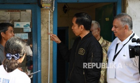 Presiden Joko Widodo (tengah) didampingi Menteri BUMN Rini Soemarno (kiri) dan Dirut PLN Sofyan Basir (kanan) menghidupkan listrik ketika meninjau penyambungan instalasi listrik gratis melalui sinergi BUMN untuk masyarakat di Bantarjati, Bogor, Jawa Barat, Ahad (2/12/2018). 