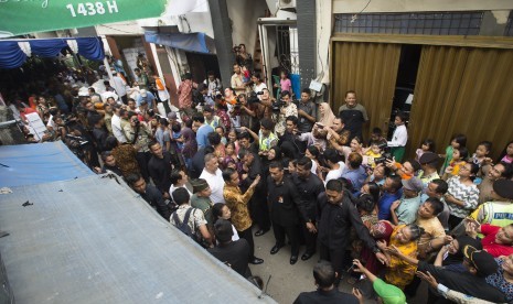 Presiden Joko Widodo (tengah) melambaikan tangan kepada warga yang mengantre pembagian sembako di Jalan Rawa Bebek II, RW. 11, RT. 7, Jakarta, Selasa (13/6). 