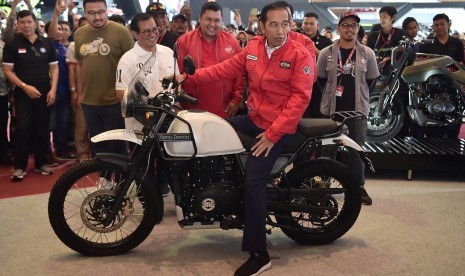 Presiden Joko Widodo (tengah) mencoba motor Royal Enfield saat mengunjungi Indonesia Motorcycle Show (IMOS) 2018 di Jakarta Convention Center, Jakarta, Sabtu (3/11/2018). 