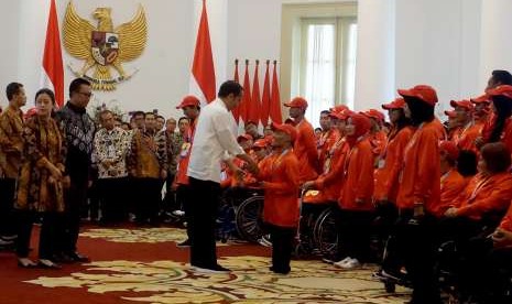 Presiden Joko Widodo (tengah) menyerahkan bonus prestasi kepada peraih perak dari cabang olahraga renang Asian Para Games 2018, Aris, sebagai perwakilan atlet, di Istana Kepresidenan Bogor, Jawa Barat, Sabtu (13/10).