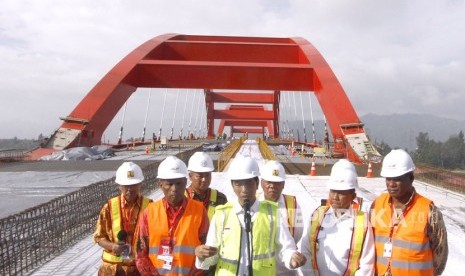 Presiden Joko Widodo (tengan) didampingi Menteri Pekerjaan Umum dan Perumahan Rakyat (PUPR) Basuki Hadimuljono (ketiga kanan) dan sejumlah pejabat daerah setempat memberi keterangan saat meninjau proyek pembangunan Jembatan Holtekamp di Jayapura, Papua, Kamis (12/4). 