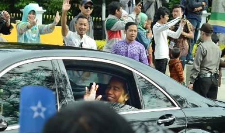 Presiden Jokowi melambaikan tangan kepada warga saat menuju tempat Konferensi Asia Afrika (KAA) ke-60, di Gedung Merdeka, Bandung, Jumat (24/4).