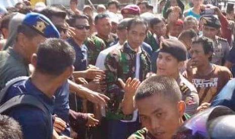 Presiden Jokowi mengenakan seragam TNI berada di tengah prajurit di Palu, Sulawesi Tengah, Ahad (30/9).