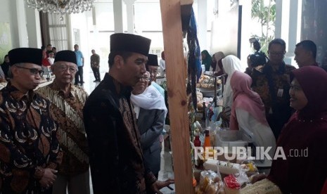 Presiden Jokowi meninjau pameran pedagang yang ikut dalam program bank wakaf mikro di Istana Negara, Rabu (28/3). 