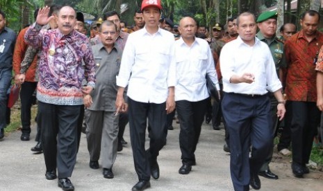 Presiden Jokowi (tengah) berjalan bersama Menteri Desa Marwan Jafar (ketiga kanan) usai melakukan peletakan batu pertama pembangunan sejumlah infrastruktur di Nagari Parit Malintang, Kecamatan Enam Lingkung, Kabupaten Padang Pariaman, Kamis (8/10).