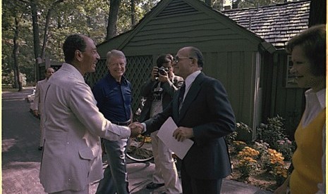 Presiden Mesir Anwar Sadat bersalaman dengan PM Israel Menachem Begin disaksikan Presiden AS Jimmy Carter di rumah peristirahatan presiden AS, Camp David 