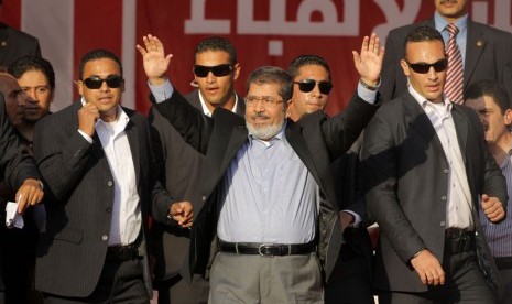   Presiden Mesir terpilih Muhammad Mursi melambaikan tangan pada puluhan ribu pendukungnya yang berkumpul di Tahrir Square, Kairo.   (Amr Nabil/AP)