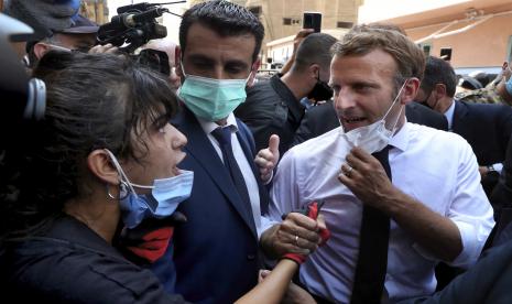  Presiden Prancis Emmanuel Macron, kanan, berbicara dengan seorang wanita saat mengunjungi lingkungan Gemayzeh, yang mengalami kerusakan parah akibat ledakan pada hari Selasa yang melanda pelabuhan Beirut, Lebanon, Kamis, 6 Agustus 2020. Macron telah tiba di Beirut untuk menawarkan dukungan Prancis ke Lebanon setelah ledakan pelabuhan yang mematikan.