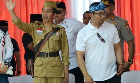 Presiden RI Joko Widodo (Jokowi) menggunakan kostum pejuang didampingi Gubernur Jawa Barat Ridwan Kamil (kanan) melambaikan tangan saat hadir pada acara Bandung Lautan Sepeda dalam rangka Hari Pahlawan, di kawasan Gasibu, Kota Bandung, Sabtu (10/11).