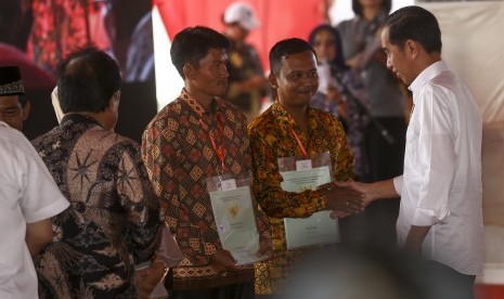 Presiden RI Joko Widodo (kanan) menyerahkan sertifikat hak atas lahan tanah kepada perwakilan masyarakat di pelataran Benteng Kuto Besak (BKB), Palembang, Sumatera Selatan, Jumat (13/7).