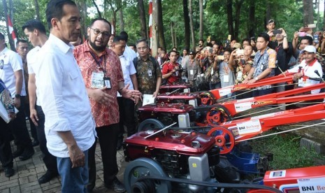 Presiden RI Joko Widodo (Kiri) meninjau mesin traktor tangan yang merupakan bantuan Corporate Social Responsibility (CSR) dari PT Bank Negara Indonesia (Persero) Tbk (BNI) kepada para petani penggarap lahan di Sumatra Selatan.