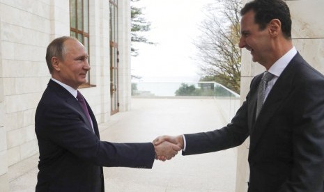 Presiden Rusia Vladimir Putin (kiri) berjabat tangan dengan Presiden Suriah Bashar Assad di kediaman Bocharov Rucheidi resor Laut Hitam Sochi, Rusia, Senin (20/11).