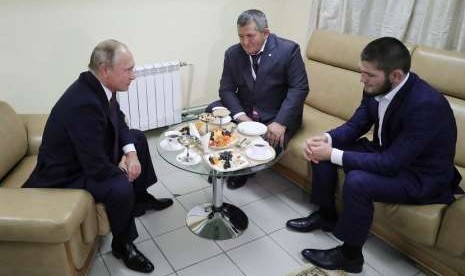  Presiden Rusia Vladimir Putin (kiri) saat berbincang dengan petarung bebas Khabib Nurmagomedov (kanan) dan pelatih serta ayah dari Khabib, Abdulmanap Nurmagomedov (tengah) di Ulyanovsk, Rusia. 