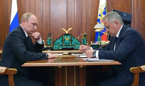 Presiden Rusia Vladimir Putin mendengarkan Menteri Pertahanan Rusia Sergei Shoigu selama pertemuan mereka di Kremlin di Moskow, Rusia, Selasa (2/7). Kebakaran di salah satu kapal selam laut angkatan laut Rusia menewaskan 14 pelaut.