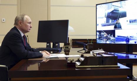 Presiden Rusia Vladimir Putin mengawasi peresmian kapal baru untuk angkatan laut Rusia melalui konferensi video di kediaman Novo-Ogaryovo di luar Moskow, Rusia, Kamis, 29 Desember 2022. Menteri Pertahanan Rusia Sergei Shoigu terlihat di layar TV di sebelah kanan.