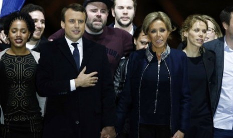 Presiden terpilih Prancis Emmanuel Macron bergandengan tangan dengan istrinya Brigitte Trogneux saat merayakan kemenangan Macron di Museum Louvre, Paris, Ahad, 7 Mei 2017.