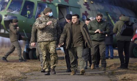 Presiden Ukraina Volodymyr Zelenskyy, tengah, tiba untuk menghadiri latihan militer di luar kota Rivne, Ukraina utara, Rabu, 16 Februari 2022. Ia mengatakan agresi terus menerus Rusia terhadap negaranya menunjukkan bahwa sanksi yang dikenakan Barat pada Moskow tidak cukup.  