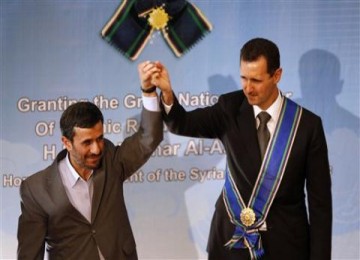 Presiden Iran Mahmoud Ahmadinejad mengangkat tangan Presiden Syria Bashar al-Assad seusai upacara penganugerahan medali kehormatan di Teheran, Iran, Sabtu.