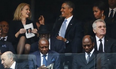 President Barack Obama (kanan) bercanda dengan PM Denmark, Helle Thorning-Schmidt, pada saat bersamaan, ibu negara AS, Michelle Obama fokus menyaksikan seremoni peringatan mantan presiden Afrika Selatan, Nelson Mandela di Stadion FNB Stadium,Soweto.