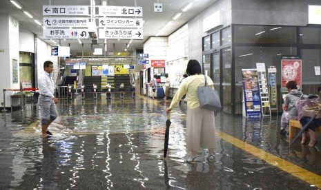 Pria berjalan melalui kawasan yang banjir di stasiun kereta di Saga, selatan Jepang, Rabu (28/8). Prefektur Saga diguyur hujan lebat sejak Rabu pagi.