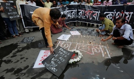 Pria meletakkan ucapan dan menyalakan lilin mengenang korban tewas akibat teror di sebuah restoran di Dhaka, Bangladesh, Sabtu (2/7).