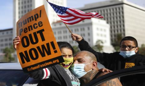 Pria mendekap putrinya dan putranya sambil membawa bendera putih merayakan kemenangan Joe Biden dan Kamala Harris, di Los Angeles, Sabtu (7/11) waktu AS. 