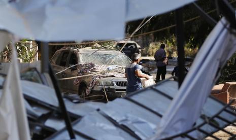  Pria menggotong barang-barangnya saat meninggalkan rumahnya yang rusak akibat ledakan di Beirut, Lebanon, Kamis (6/8). Tentara Lebanon menggunakan buldozer menyapu jalanan yang tertutup puing dan kaca. Pemerintah mulai menginvestigasi penanggung jawab ledakan. Sejumlah pihak di pelabuhan juga akan dikenai tahanan rumah. 