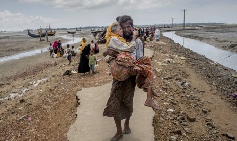 Pria Rohingya Abdul Kareem berjalan menuju kamp pengungsi menggendong ibunya Alima Khatoon setelah menyeberang dari Myanmar menuju Bangladesh, di Teknaf, Bangladesh, (16/9).