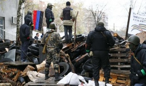 Pro-Russian men stand guard at a barricade near the police headquarters in Slaviansk April 13, 2014. 