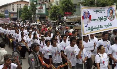 Protesters march with a banner showing pictures of Myanmar President Thein Sein (left) and UN human rights envoy Tomas Ojea Quintana (reading 