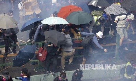 Mahasiswa pengunjukrasa lari saat dibubarkan polisidi area kampus Hong Kong Polytechnic University. Polisi mengepung kampus dengan ratusan mahasiswa pengunjukrasa di dalamnya