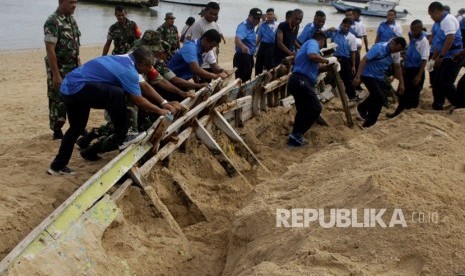 Puluhan anggota TNI AL Lantamal VII Kupang bersama TNI-AD berusaha mengeluarkan bangkai perahu yang tertanam di dalam pasir saat dilaksanakannya aksi bersih pantai memperingati Hari Dharma Samudera di Pesisir Pantai Pasing Panjang, Kota Kupang, NTT, Senin (14/1/2019).