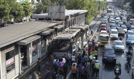 Puluhan kendaraan melintas di samping Bus Transjakarta yang terbakar di Halte Universitas Indonesia (UI) Salemba, Jakarta, Jumat (3/7). 