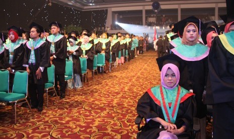 Putri (menggunakan kursi roda), salah satu wisudawati Universitas BSI (UBSI).