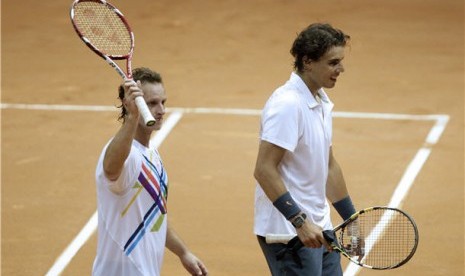 Rafael Nadal (kanan) bersama David Nalbandian meninggalkan lapangan usai menaklukan ganda Spanyol, Pablo Andujar/Guillermo Garcia-Lopez, di putaran pertama turnamen Brazil Terbuka di Sao Paulo, Brazil, Selasa (12/2). 