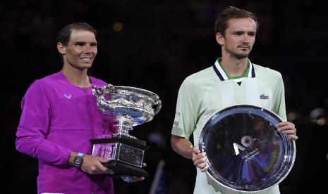 Rafael Nadal (kiri) dari Spanyol memegang Piala Tantangan Norman Brookes setelah mengalahkan Daniil Medvedev dari Rusia di final tunggal putra kejuaraan tenis Australia Terbuka di Melbourne, Australia, Ahad (30/1/2022).. 