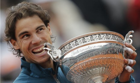 Rafael Nadal, petenis asal Spanyol, menggigit trofi usai mengalahkan petenis sesama Spanyol, David Ferrer, di partai final Prancis Terbuka 2013 di Roland Garros, Paris, Ahad (9/6). 