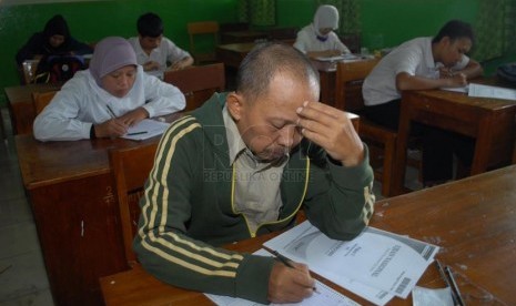 Rafiudin (45) saat mengerjakan ujian paket C di SMPN 216 Jakarta, Rabu (16/4).