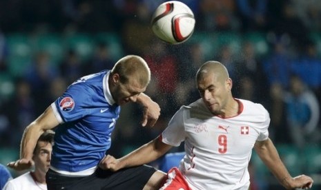 Ragnar Klavan (kiri) berduel dengan pemain Swiss Eren Derdiyok. Klavan mencetak gol bunuh diri yang membuat Swiss mengalahkan Estonia 1-0.