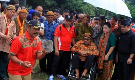 Raja Keraton Kasunanan Surakarta Hadiningrat Pakubowono XIII (duduk di kursi roda) menyaksikan prosesi simbolik peletakan batu pertama pembangunan Pasar Darurat Klewer oleh Walikota Solo, Fx Hadi Rudyatmo (kiri) di Alun-alun Utara keraton setempat, Solo, Jawa Tengah, 6 April 2015. 