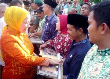 Ratu Atut Chosiyah (kiri), Gubernur Banten, membagikan Alquran Mushaf Al-Bantani kepada masyarakat. 