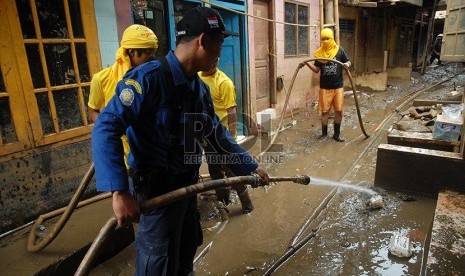 Petugas Sudin Pemadam Kebakaran Jakarta Timur membersihkan lumpur sisa banjir di pemukiman warga Kampung Pulo, Jatinegara, Jakarta, Kamis (13/2).  (Republika/Rakhmawaty La'lang)