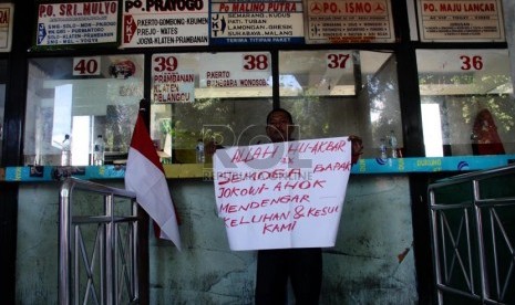    Seorang pengunjuk rasa membawa poster saat menolak penutupan terminal Lebak Bulus, Jakarta, Senin (6/1).    (Republika/Yasin Habibi)