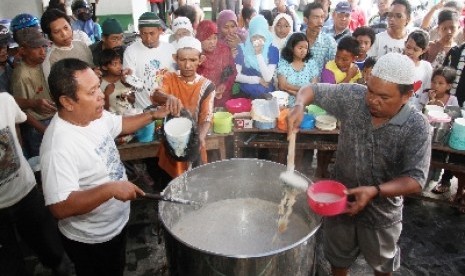 Ratusan warga saling berebut bubur samin yang dibagikan petugas Masjid Darussalam di Solo, Jawa Tengah.