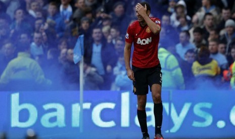 Reaksi pemain Manchester United Rio Ferdinand, setelah dihantam oleh sebuah benda yang dilemparkan dari arah penonton saat bertanding melawan Manchester City di Stadion Etihad di Manchester,Ahad (9/12). (Reuters/Phil Noble)