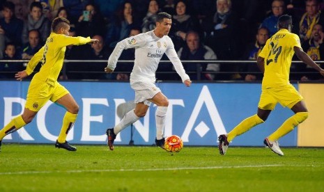 Real Madrid's Portuguese striker Cristiano Ronaldo (C) controls the ball next to Villarreal CF's Mexican Jonathan Dos Santos (L) and Ivory Eric Bailly (R) during their Spanish Liga Primera Division soccer match played at El Madrigal stadium, in Villarreal,