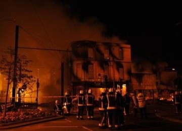 Regu pemadam kebakaran Inggris berusaha menguasai api dari sebuah gedung yang dibakar perusuh