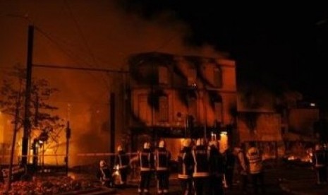 Regu pemadam kebakaran Inggris berusaha menguasai api dari sebuah gedung yang dibakar perusuh