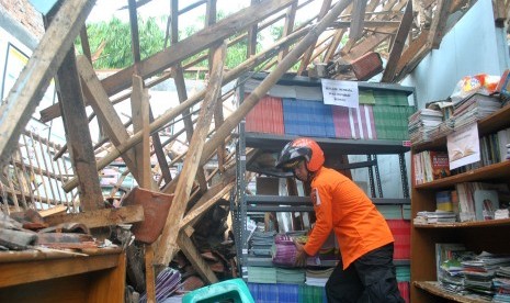 Relawan Badan Penanggulangan Bencana Daerah (BPBD) Kota Bogor mengangkat buku pelajaran dari ruang perpustakaan yang ambruk di SDN Pakuan, jalan Dahlia, Kelurahan Pakuan, Kota Bogor, Jawa Barat, Minggu (12/2).